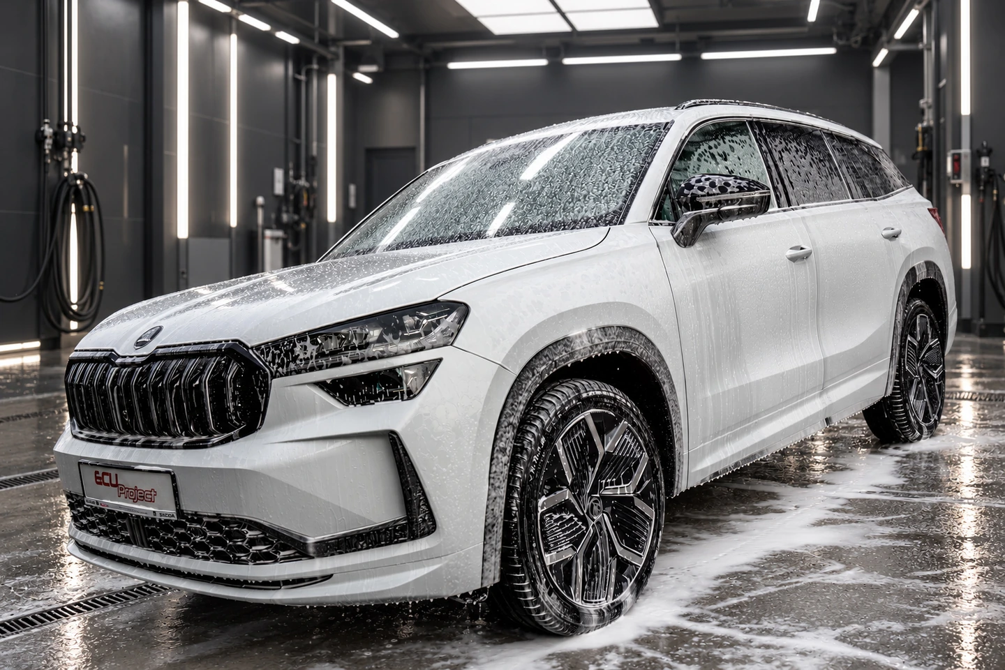Biała Škoda Kodiaq pokryta aktywną pianą podczas mycia w studiu detailingu.